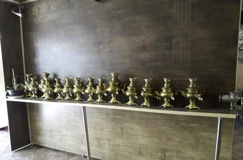 دکوراسیون سفره خانه سنتی شب های شیدایی با ردیفی از سماورهای برنزی و قدیمی بر روی میز چوبی، فضایی دلنشین و جذاب.