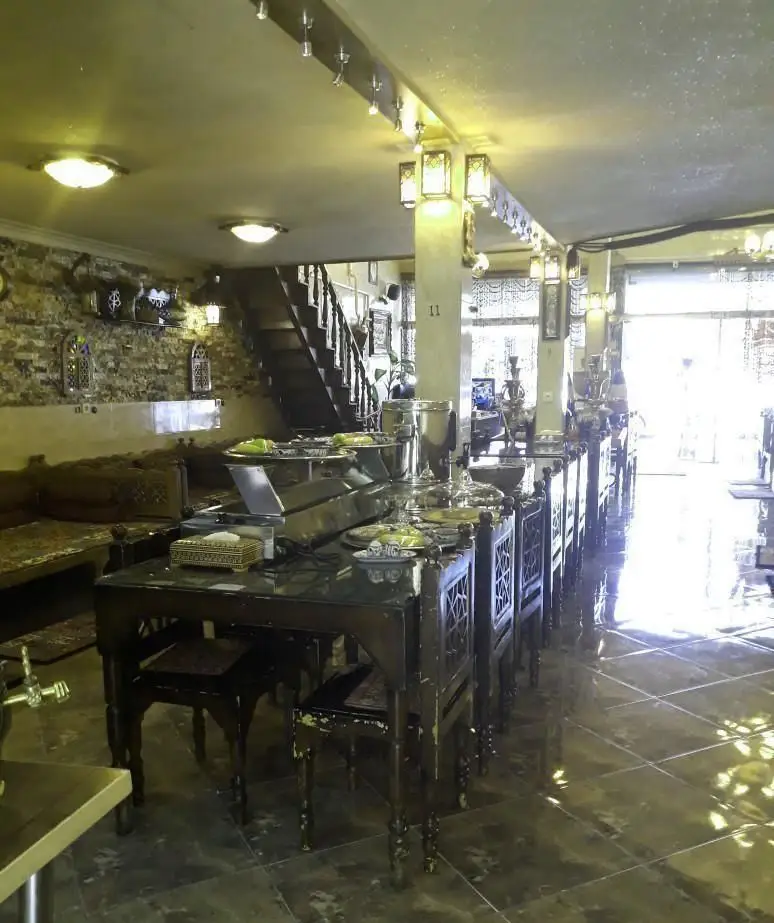 فضای داخلی سفره خانه سنتی شب های شیدایی با میز و صندلی چوبی سنتی، بوفه غذا و دکوراسیون اصیل ایرانی.