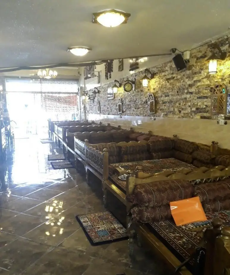 تصویری از فضای داخلی گرم و دلنشین سفره خانه سنتی شب های شیدایی با تخت های چوبی، دکوراسیون آجری و نورپردازی جذاب.