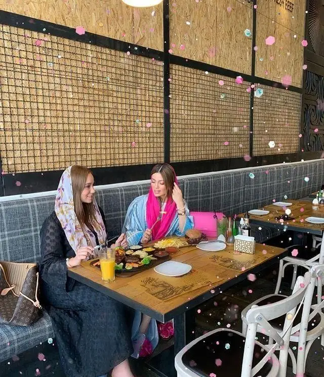 دو خانم در حال لذت بردن از غذاهای متنوع در رستوران ای تی اف. فضایی دلنشین با دکوراسیون مدرن و چوبی، مناسب برای دورهمی دوستانه و تجربه غذایی متفاوت.