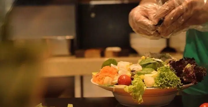 تهیه سالاد تازه و مقوی با سبزیجات رنگارنگ توسط پرسنل رستوران ای تی اف، تضمین کیفیت و طعم عالی برای مشتریان.