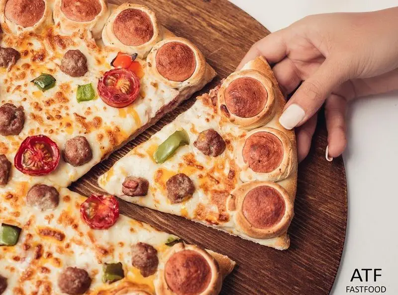 تصویری از پیتزا مخصوص رستوران فست فود ای تی اف با کراست سوسیس، کوفته قلقلی، پنیر و مخلفات تازه، انتخابی لذیذ.