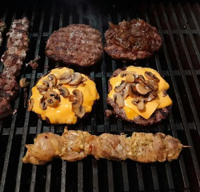 برگرهای آبدار گوشت ارگانیک با پنیر و قارچ، کباب کوبیده و جوجه کباب در حال گریل شدن، آماده برای یک وعده لذیذ.