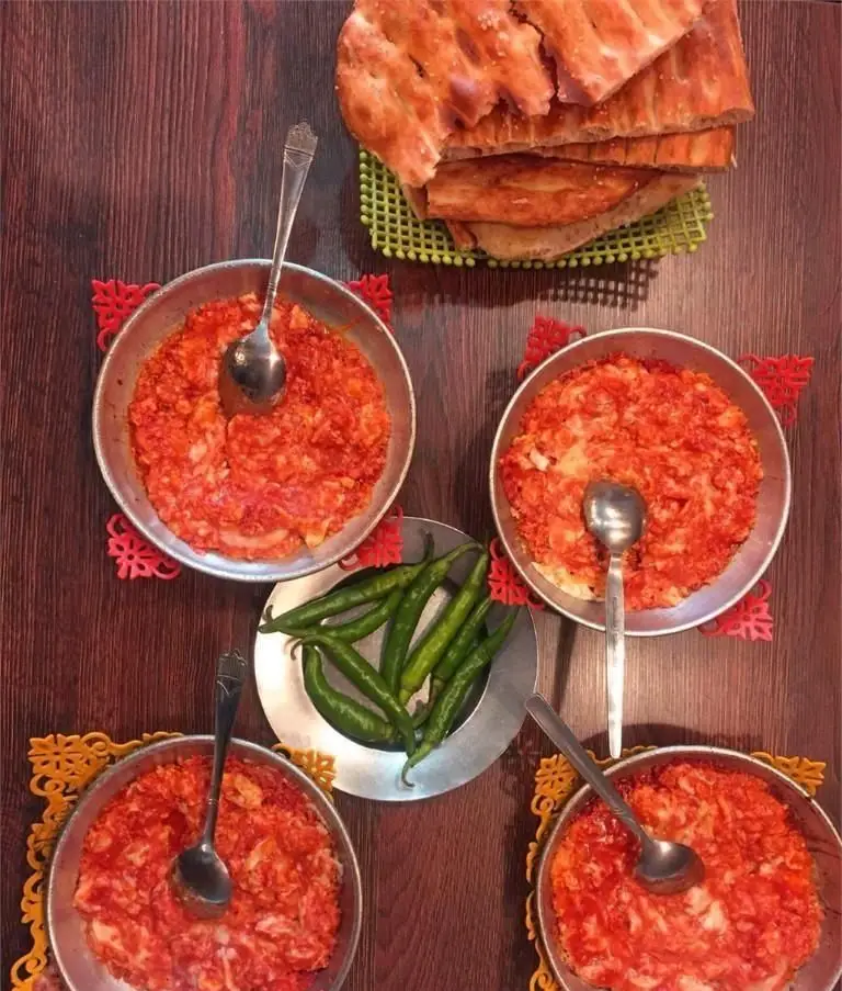 میز غذای سنتی ایرانی در رستوران غذاکده طوس: کاسه‌های پر از خوراک خوشرنگ، نان داغ تنوری و فلفل تازه. طعم اصیل ایرانی.