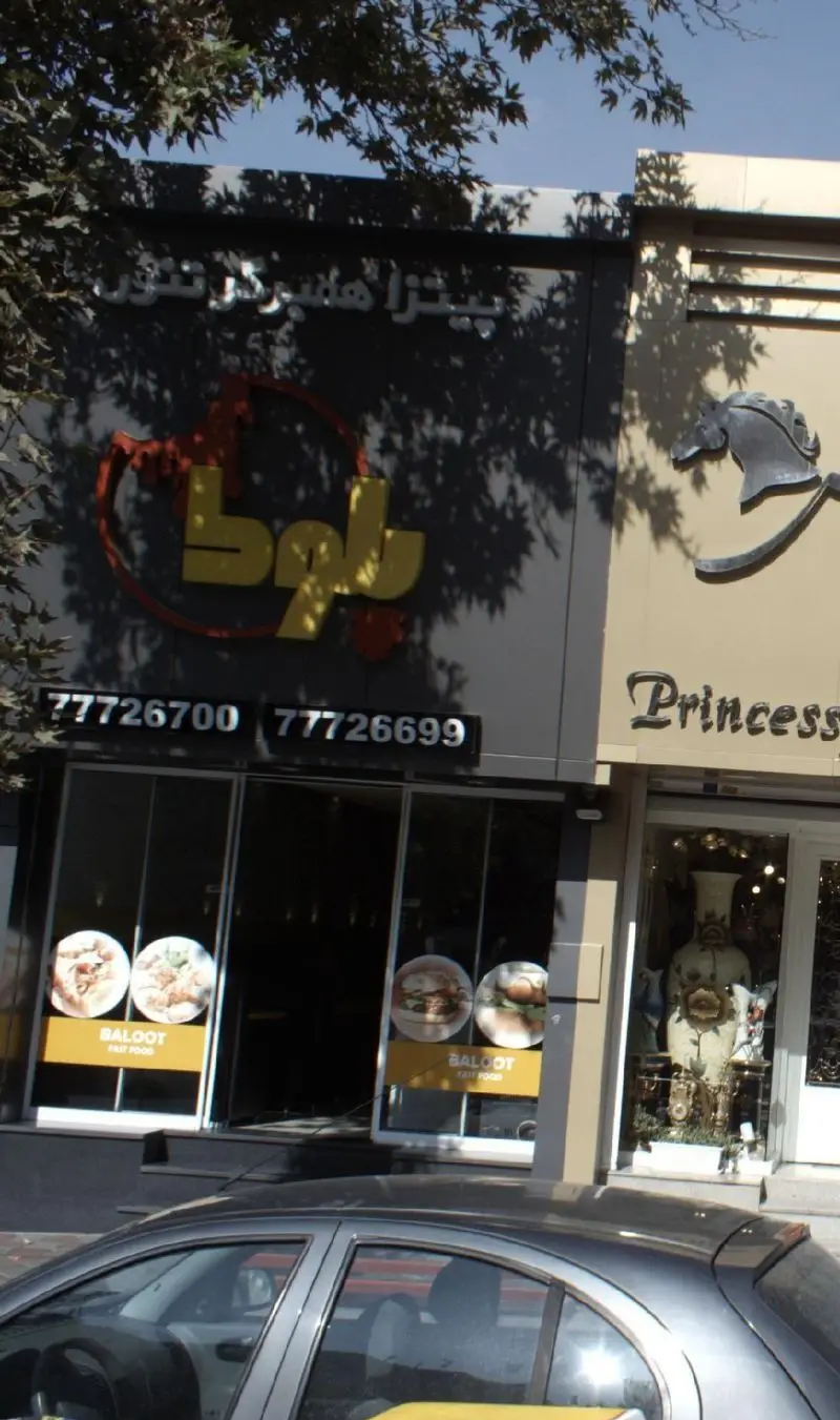 فست فود بلوط با نمای بیرونی و تابلو شامل پیتزا و همبرگر تنوری، همراه با تصاویر غذا و شماره تلفن‌های 77726700 و 77726699.