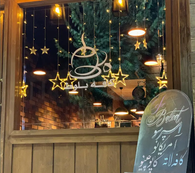 ویترین شیک شب فست فود و کافه بلوط با چراغ‌های ریسه‌ای ستاره‌ای و لوگوی کافه، نمایی گرم و دلپذیر برای مشتریان.