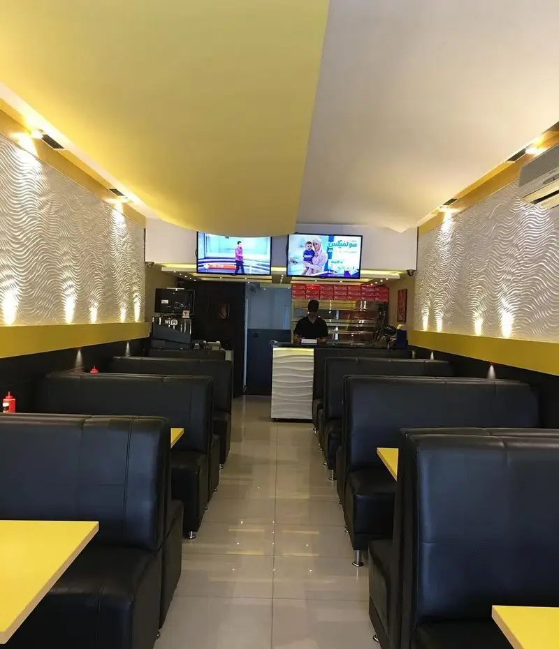 فضای داخلی شیک و مدرن فست فود بلوط با میز و صندلی‌های راحت و دکوراسیون دیواری موج‌دار، مکانی دنج برای مشتریان.