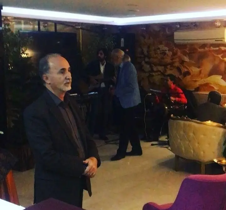 مردی در کافه رستوران سنتی دیبا با فضای دلنشین و دکوراسیون اصیل، در حال تماشای اجرای موسیقی زنده و لذت بردن از لحظات.