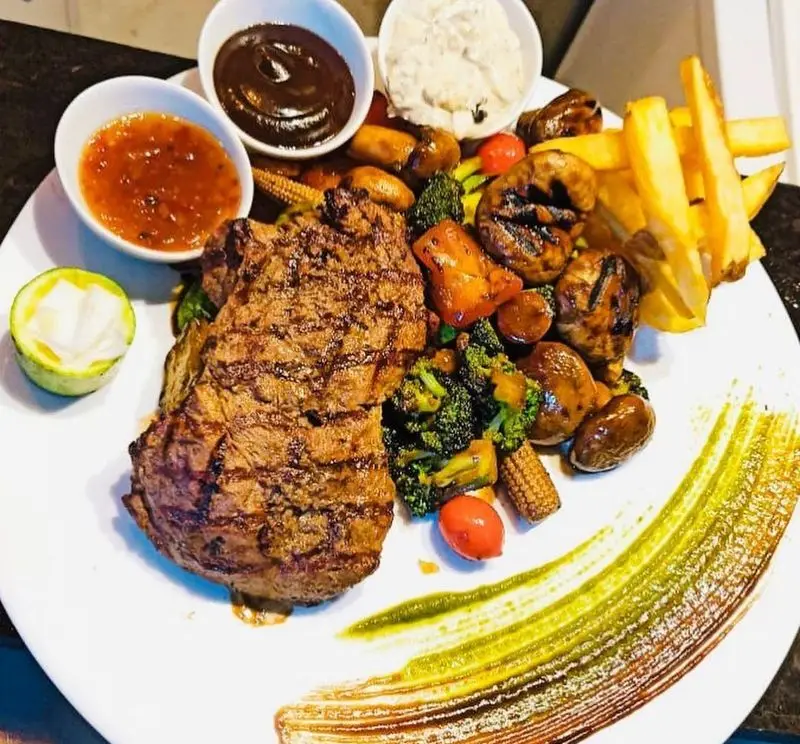 استیک گریل شده آبدار با دورچین متنوع شامل سبزیجات تازه سوت شده، سیب زمینی سرخ کرده و سس‌های مخصوص در کافه رستوران سنتی دیبا.
