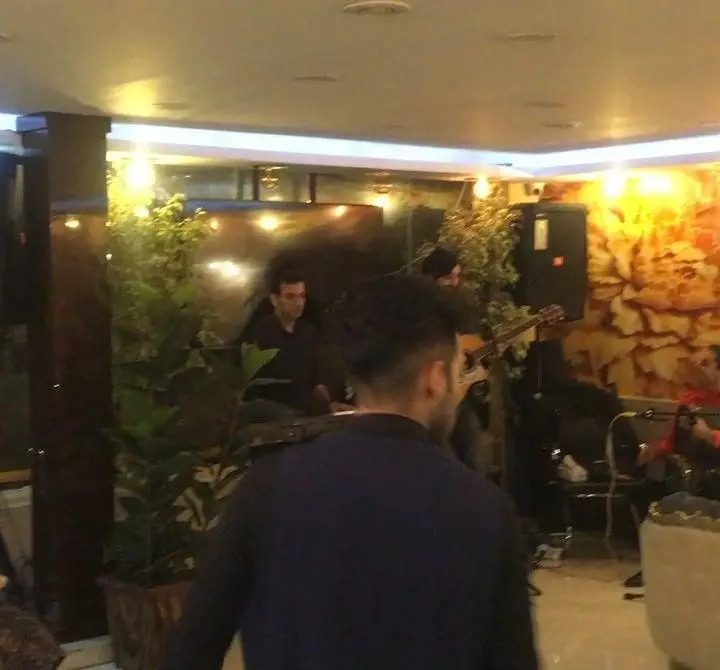 نمای داخلی کافه رستوران سنتی دیبا با اجرای زنده موسیقی توسط گروه نوازندگان و فضای صمیمی با گیاهان و نورپردازی دلنشین.