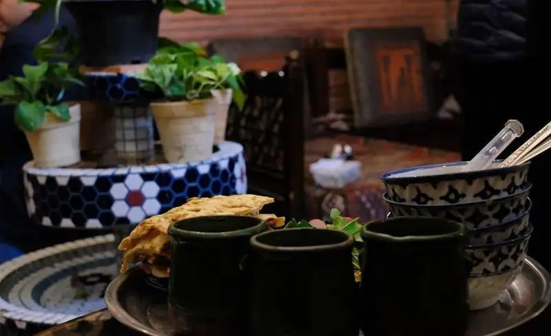 فضای سنتی و گرم سفره خانه کریم خان با دیزی، نان داغ و ظروف آبی و سفید. محیطی دلنشین برای تجربه غذای ایرانی اصیل.