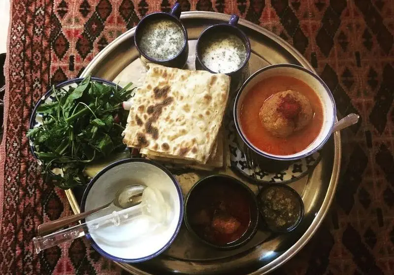 سفره خانه سنتی کریم خان: سینی غذای سنتی ایرانی با کوفته خوشمزه در سس گوجه، نان داغ، سبزی خوردن تازه، دوغ خنک و ماست محلی.