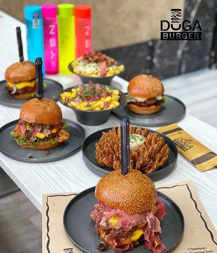 تصویری جذاب از منوی کامل دوگا برگر: انواع برگرهای لذیذ گوشت و مرغ، سیب زمینی سرخ کرده با بیکن و پنیر، و پیاز سوخاری گل.