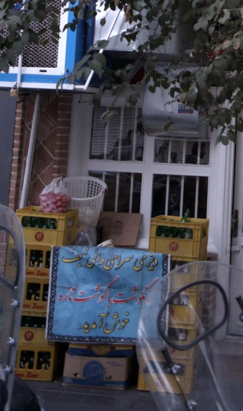 بنر دیزی سرای دائی نجف، ارائه دهنده دیگوشت با گوشت تازه، در ورودی رستوران با صندوق‌های نوشیدنی زمزم و محصولات تازه.