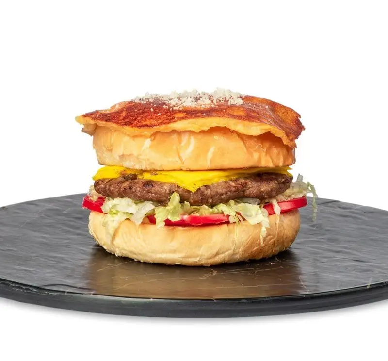 همبرگر ویژه فست فود کامنت با نان پنیری طلایی، گوشت آبدار، پنیر چدار، کاهو و گوجه فرنگی تازه، مناسب برای یک وعده غذایی لذیذ.