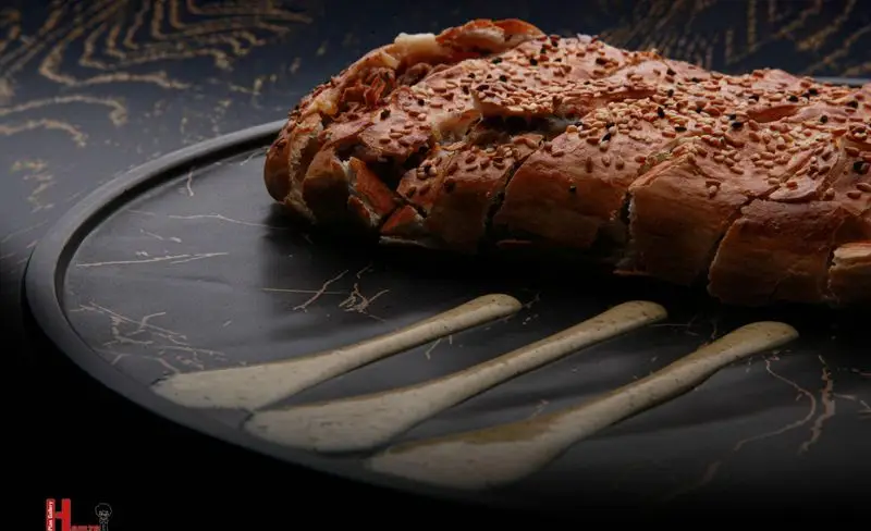 نان سیر چاک دار و پنیری خوشمزه فست فود کامنت روی سینی مرمری با سس مخصوص، یک پیش غذای عالی و جذاب برای مشتریان.