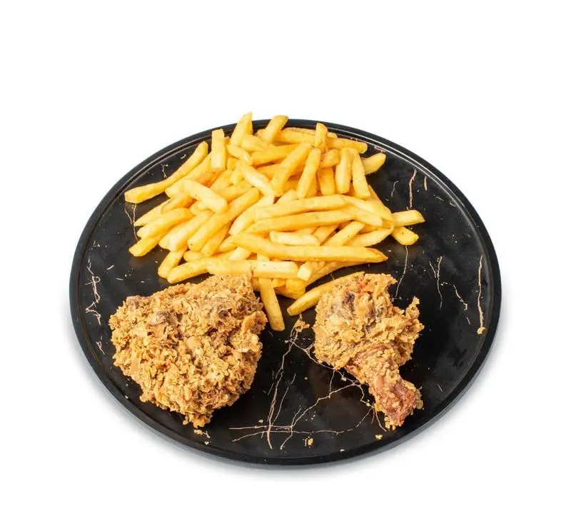 مرغ سوخاری ترد و طلایی با سیب‌زمینی سرخ کرده داغ روی بشقاب مشکی در فست فود کامنت، یک غذای خوشمزه و کامل.