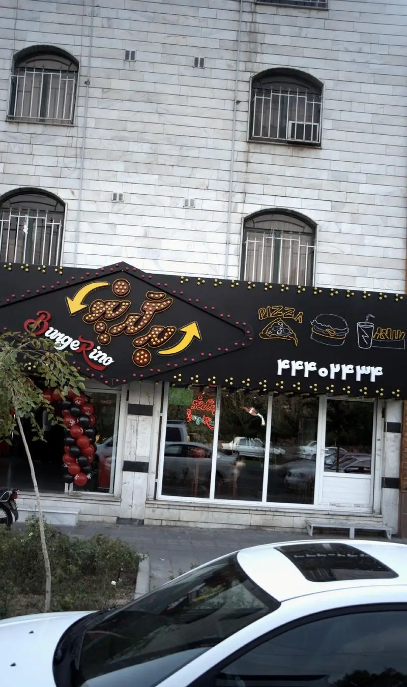 نمای بیرونی فست فود برگرینو با تابلو مشکی پیتزا برگر، شامل نام BurgerRino و لوگوهای غذاهای فست فود.