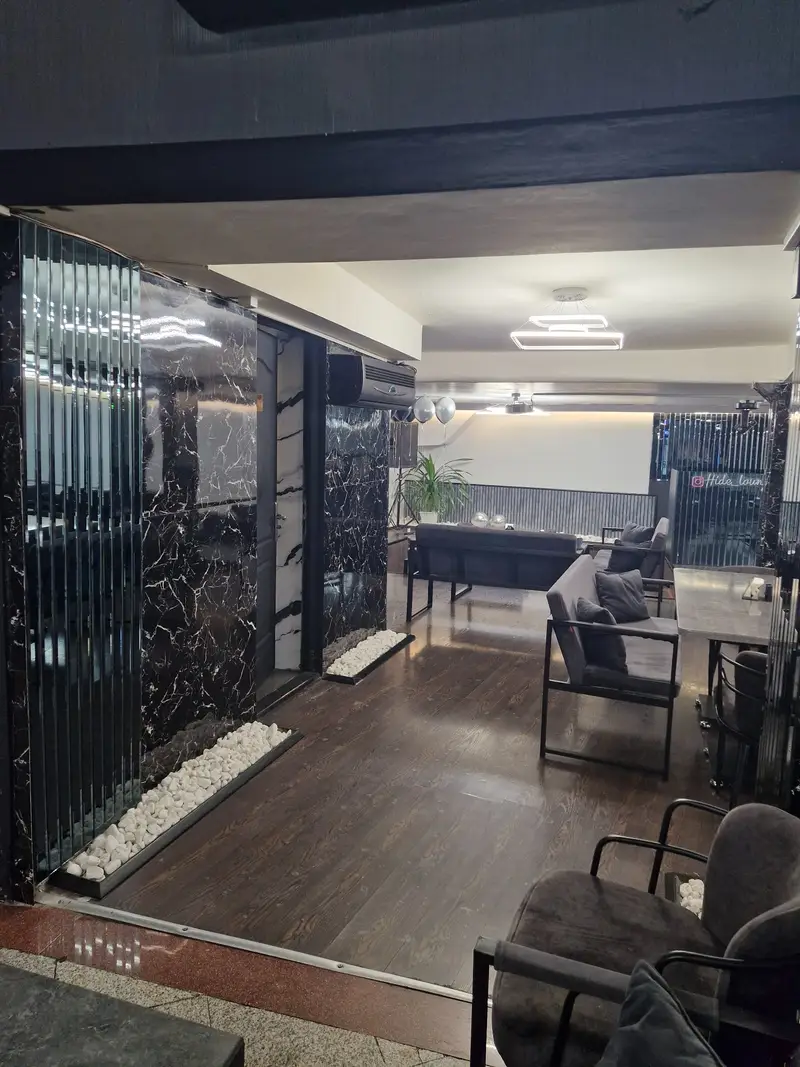 کافه رستوران هاید لانژ: فضایی شیک و مدرن با دیوارپوش مرمری مشکی، مبلمان راحتی، کفپوش چوبی و نورپردازی آرامش‌بخش.