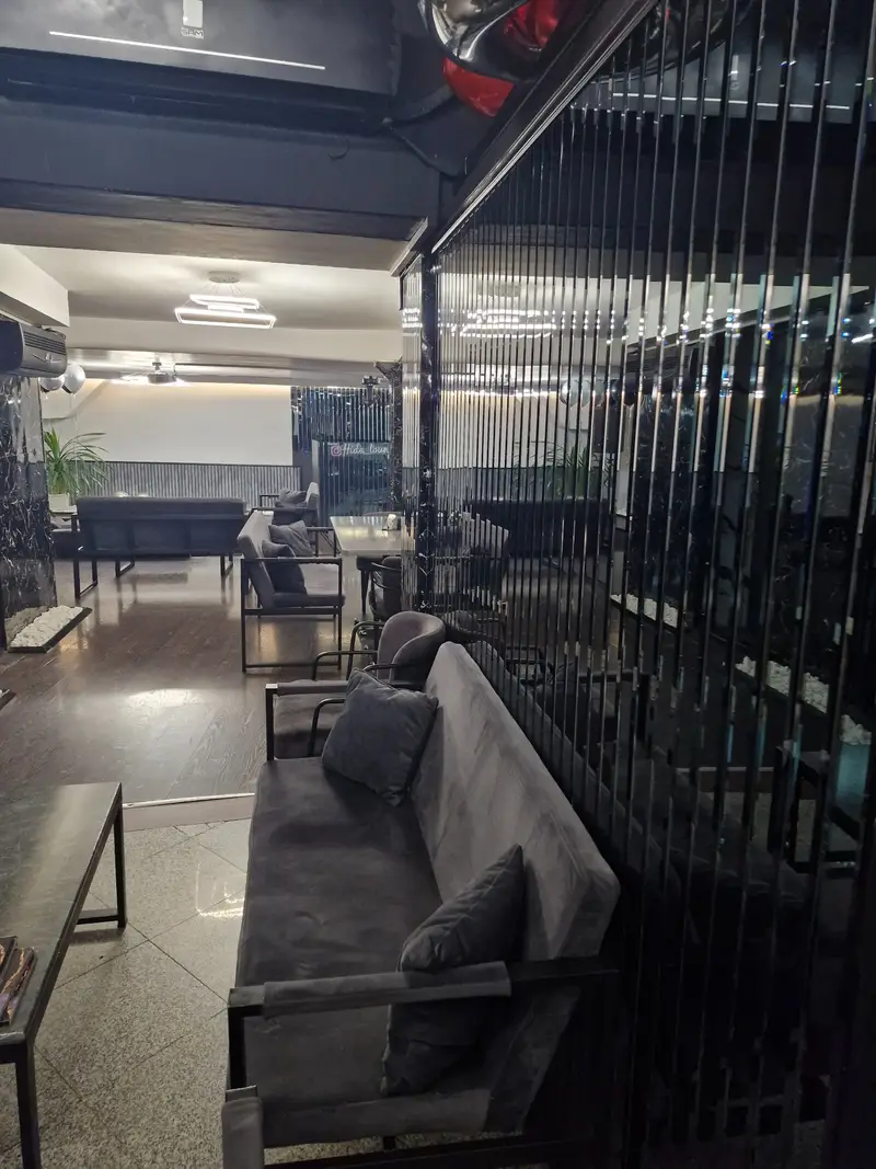 فضای داخلی کافه رستوران هاید لانژ با دکوراسیون مدرن و لوکس، مبلمان راحتی طوسی و دیوارهای براق مشکی، فضایی شیک و دلنشین.