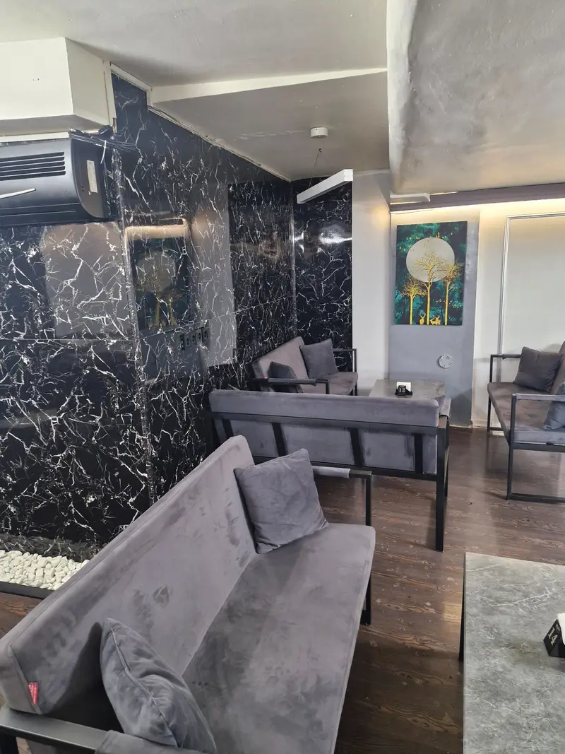 کافه رستوران هاید لانژ، محیطی لوکس و آرام با دکوراسیون داخلی مدرن، مبلمان راحتی طوسی، دیوارهای طرح مرمر و فضای دوستانه.