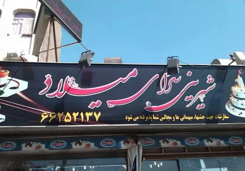تصویر تابلوی مغازه شیرینی میلاد با طراحی زیبا، نمایشگر شماره تماس ۶۶۲۵۲۱۳۷. انواع سفارشات کیک و شیرینی برای جشن‌ها، میهمانی‌ها و مجالس شما پذیرفته می‌شود.
