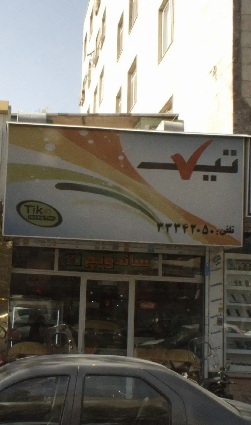 تابلوی مغازه فست فود تیک با لوگوی "Tik Healthy Food"، شماره تلفن ۵۰-۳۳۴۲ و نام "ساندویچ". نمای کلی کسب و کار غذایی تیک.