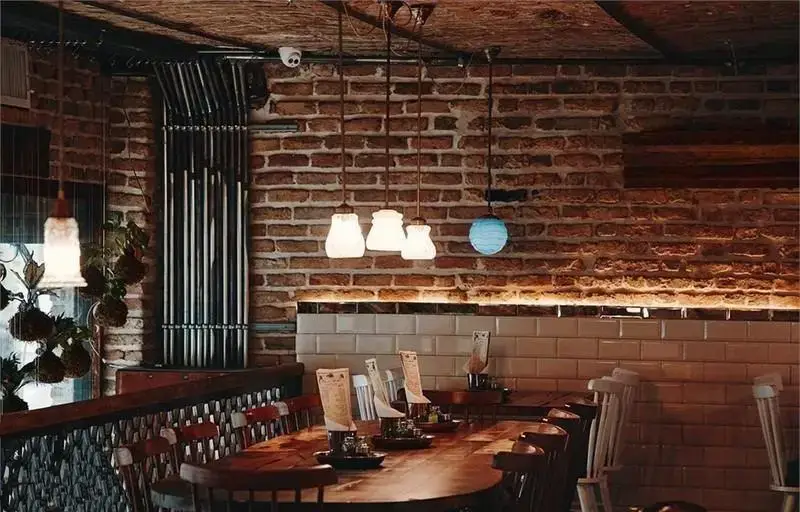 دکوراسیون داخلی گرم و دلنشین رستوران ایرانی چارگاه با دیوارهای آجری، میز و صندلی‌های چوبی و نورپردازی جذاب.
