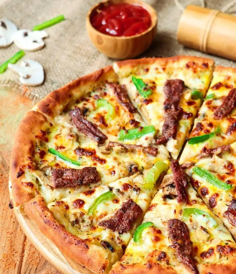 پیتزا گوشت و قارچ خوشمزه و داغ رستوران شیلا با پنیر فراوان و فلفل دلمه سبز، آماده سرو. تجربه‌ای عالی از طعم بی‌نظیر.