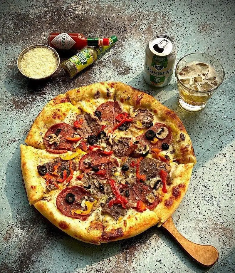 پیتزای بزرگ و پرملات کافه رستوران شاندیز گالریا با پپرونی، قارچ، زیتون، گوشت، پنیر و سس‌های تند، همراه نوشیدنی.