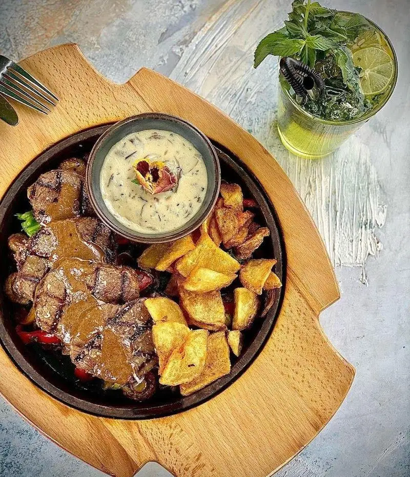 استیک گریل آبدار، سس قارچ و سیب زمینی ترد با موهیتو خنک. لذت غذای دلپذیر در کافه رستوران شاندیز گالریا.