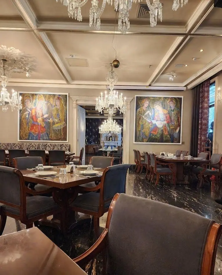 فضای داخلی مجلل کافه رستوران شاندیز گالریا با لوسترهای کریستالی خیره‌کننده، تابلوهای هنری چشم‌نواز و مبلمان شیک.