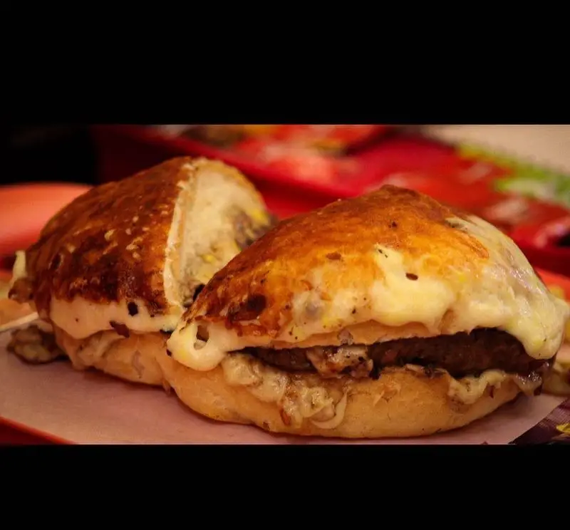 تصویری نزدیک از دو برگر پنیری و داغ با نان برشته طلایی و لایه ای سخاوتمندانه از پنیر ذوب شده، یک غذای فست فود جذاب از پیتزا هات.