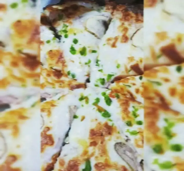 اسلایس‌های پیتزا هات با سس سفید خامه‌ای، پنیر طلایی و سبزیجات سبز تازه، غذایی خوشمزه و اشتهاآور.