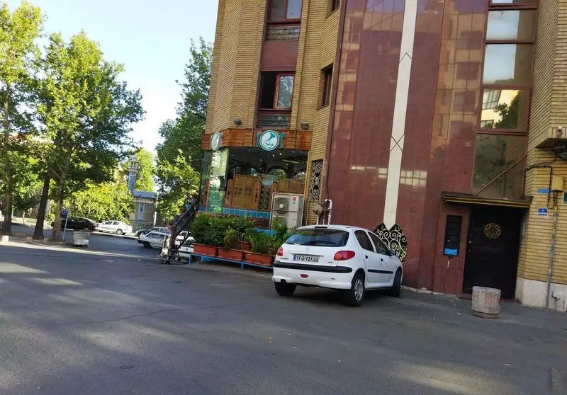 نمای بیرونی و روزانه رستوران مرشد باهنر با ویترین شیشه‌ای، ساختمان آجری و یک خودروی سفید پارک شده در خیابان