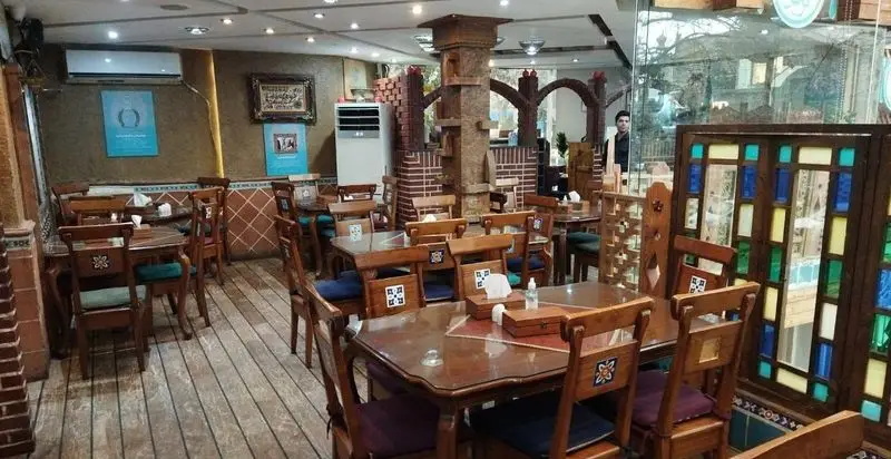 فضای داخلی رستوران مرشد باهنر با دکوراسیون سنتی، میز و صندلی‌های چوبی شیک و محیطی آرام و دلنشین آماده پذیرایی از میهمانان.