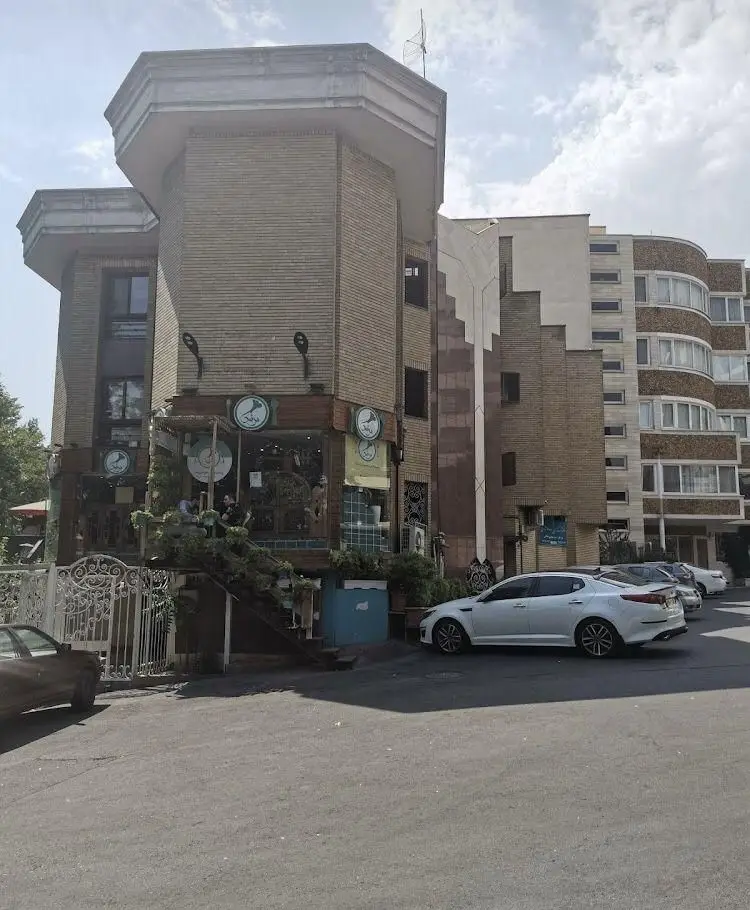 رستوران مرشد باهنر: نمای بیرونی ساختمان آجری با سقف هشت ضلعی، ورودی پلکانی و لوگوهای رستوران در فضای شهری تهران.