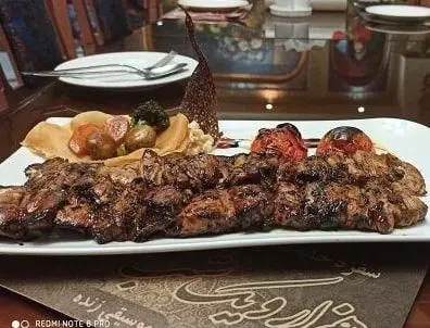 کباب میکس گوشت تازه آبدار با گوجه کبابی و دورچین مخصوص، غذای لذیذ و اصیل ایرانی در رستوران هزارویک شب.