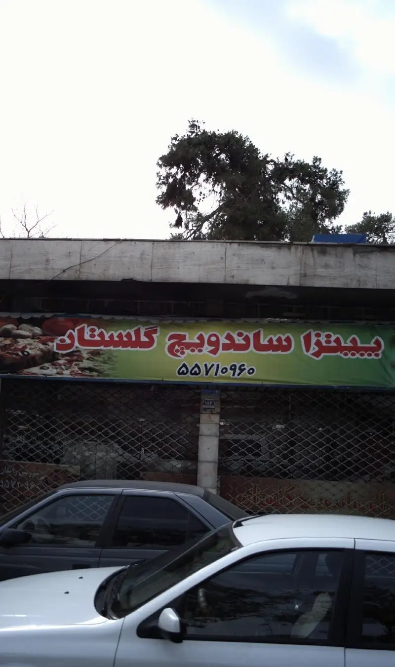 تابلوی سبز رنگ فست فود پیتزا ساندویچ گلستان حاوی نام کامل، شماره تماس ۵۵۷۱۰۹۶۰ و تصاویر اشتها آور پیتزا و ساندویچ.