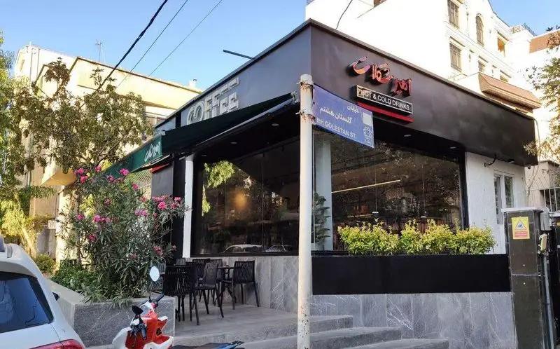 کافه امیر شکلات: نمای خارجی این کافه در خیابان گلستان هشتم تهران، با تابلو 'HOT & COLD DRINKS' و فضایی دنج برای انواع نوشیدنی.