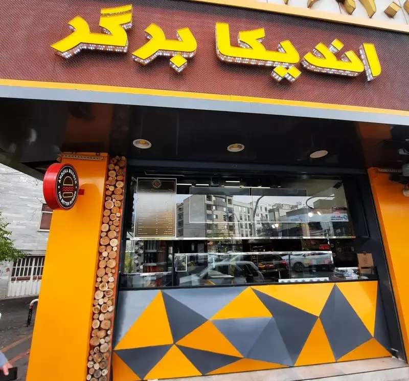 نمای بیرونی فست فود اندیکا برگر با تابلوی درخشان زرد و مشکی، مکانی مناسب برای تجربه طعم لذیذ برگر در شهر.