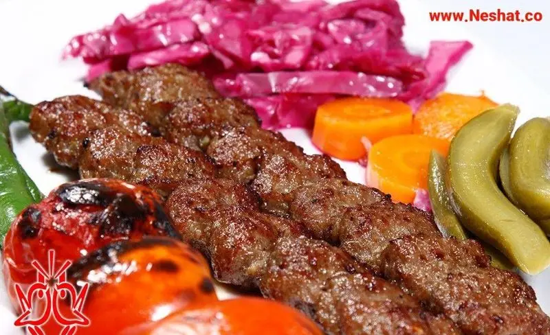کباب کوبیده آبدار رستوران نشاط با گوجه کبابی، فلفل سبز، ترشی کلم قرمز، هویج و خیارشور. یک غذای لذیذ ایرانی.