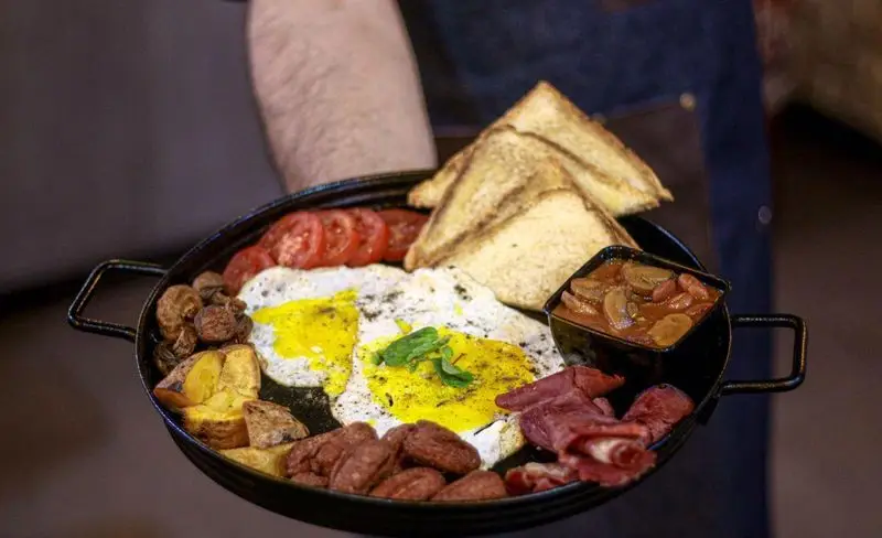 صبحانه انگلیسی کامل کافه فست فود برج برگر: بشقاب بزرگ با تخم مرغ، سوسیس، بیکن، لوبیا، قارچ، سیب زمینی و نان تست.