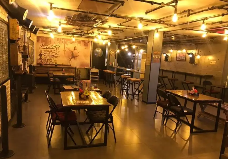 فضای داخلی کافه فست فود برج برگر، با دکوراسیون صنعتی منحصر به فرد، نورپردازی گرم و میز و صندلی‌های مدرن، محیطی دلپذیر برای مشتریان.