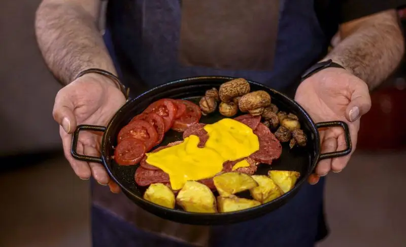 بشقاب صبحانه/برانچ مخصوص کافه فست فود برج برگر: سوسیس پنیردار، گوجه، قارچ و سیب زمینی، توسط سرآشپز سرو می‌شود. غذایی خوشمزه و کامل.