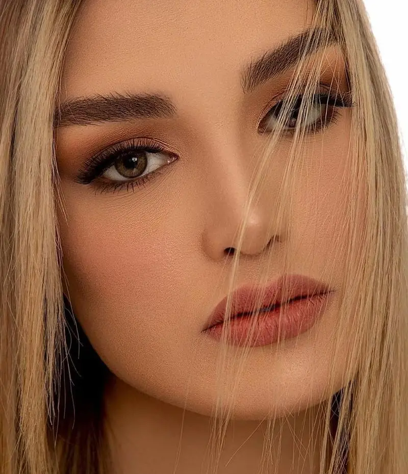 پرتره نزدیک از چهره زن با میکاپ لایت و نود بسیار شیک، مدل سایه چشم قهوه ای ملایم و رژلب مات مناسب آرایش روزانه دخترانه