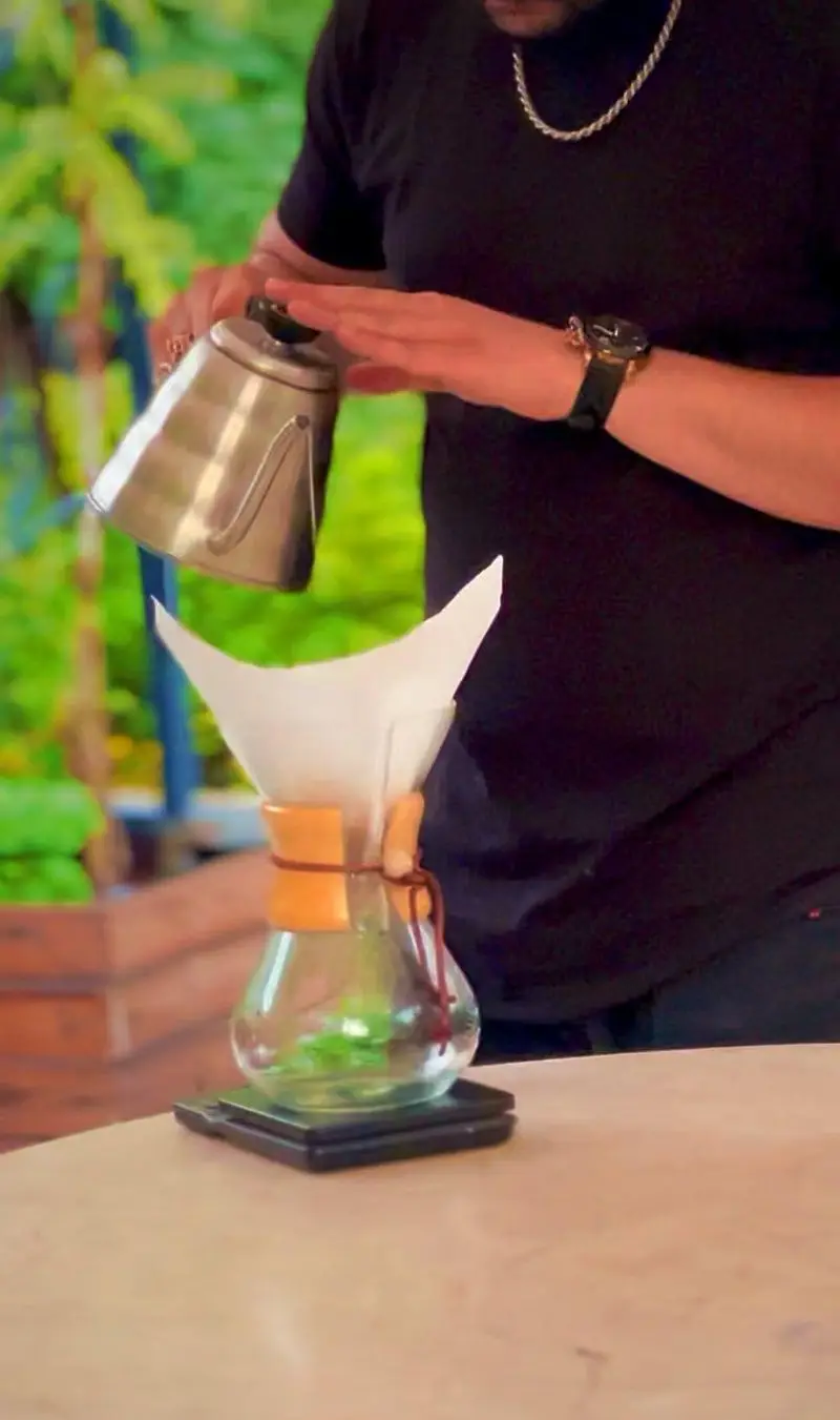 آماده سازی قهوه دمی با کمکس در کافه رستوران گجا. باریستا با کتری گردن غازی آب را روی فیلتر قهوه می ریزد. تجربه ای دلنشین از قهوه تازه.