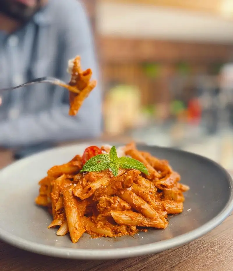 پاستا پنه با سس گوجه‌فرنگی، تزئین شده با نعناع، غذایی لذیذ در کافه رستوران گجا، انتخابی عالی برای یک وعده خاص.