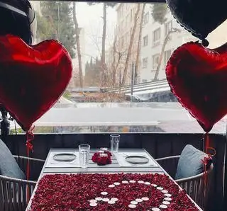 میز آرایی رمانتیک و دکوراسیون عاشقانه کافه رستوران گجا با گلبرگ های رز قرمز، شمع ها و بادکنک قلبی برای قرارها و مناسبت های خاص.