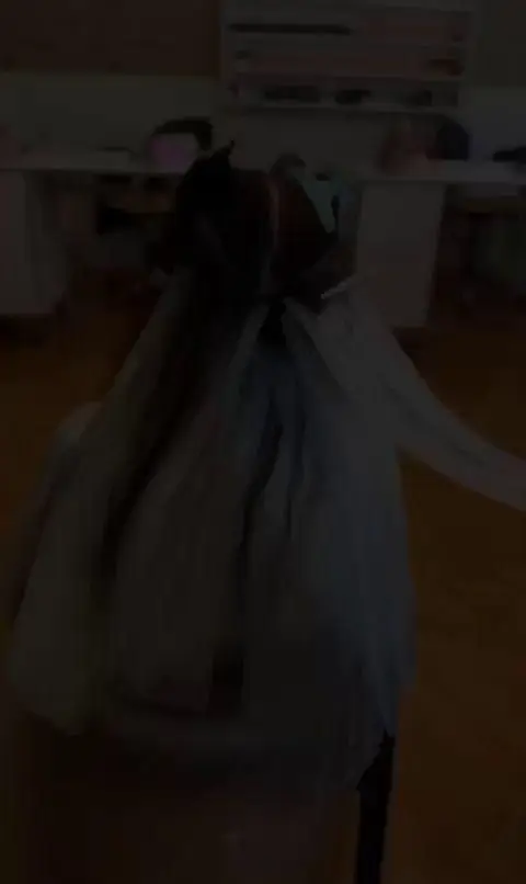 تصویری از پشت سر یک فرد در سالن زیبایی پدیده نو، با موهایی بلند و تیره که به نظر میرسد در حال حالتدهی است. محیط سالن تاریک است.
